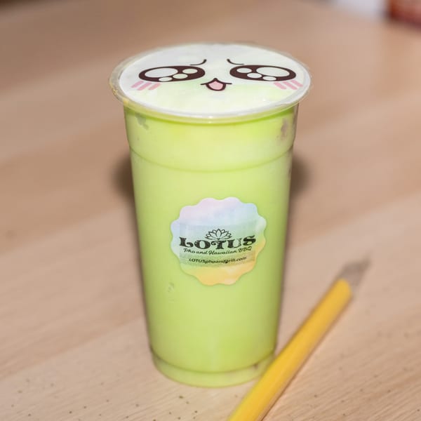 A green boba drink from Lotus Pho and HAWAIIAN BBQ with a cute face on the lid.