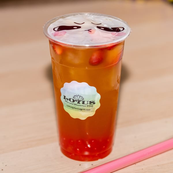 A Lotus Pho and Hawaiian BBQ fruit tea with strawberries and popping boba, and a pink straw.